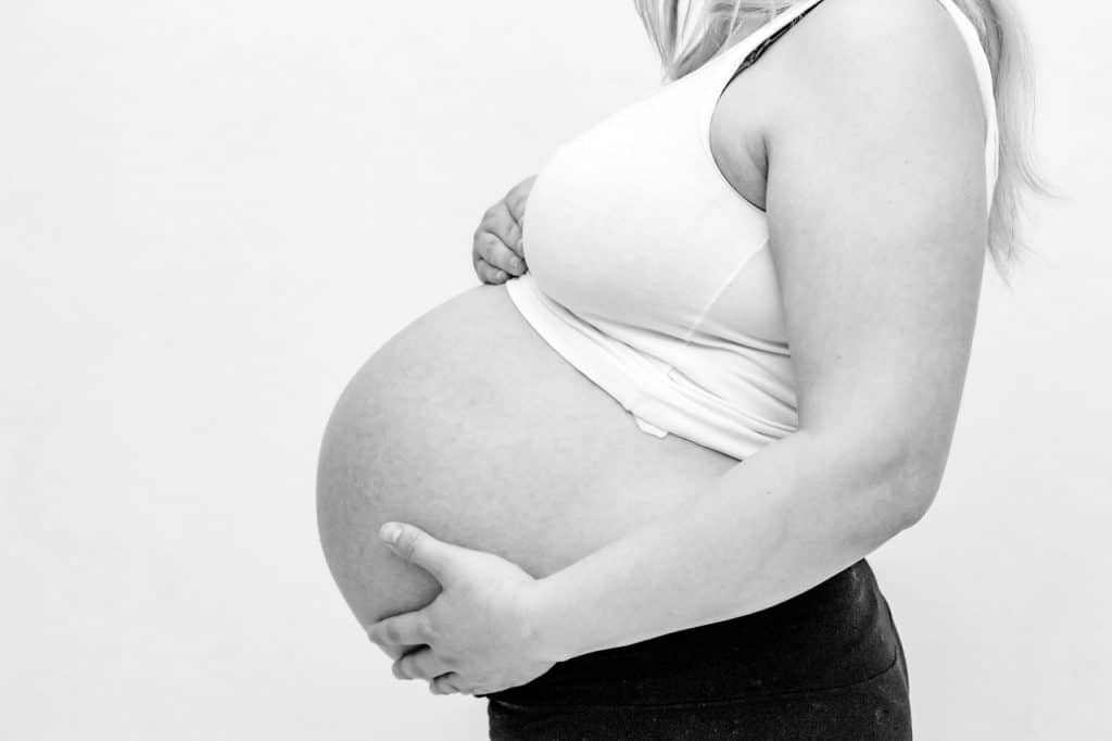 אישה בהריון מחזיקה בבטן - תמונה בשחור לבן